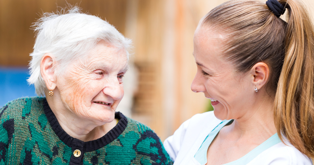 A professional caregiver compassionately hugs a senior client.