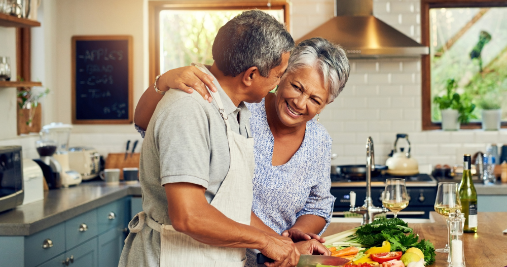 A senior couple enjoys cooking a healthy meal together, representing National Nutrition Month.