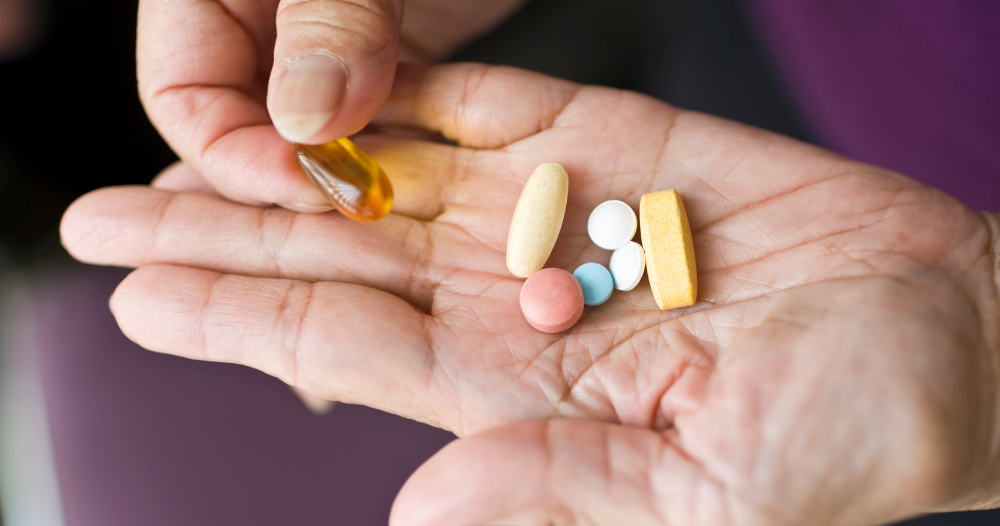 A woman holds pills in her hand, representing medication management.