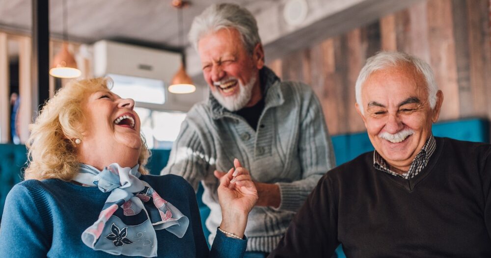 Older adults laugh and enjoy each other’s company representing how socialization can help seniors.