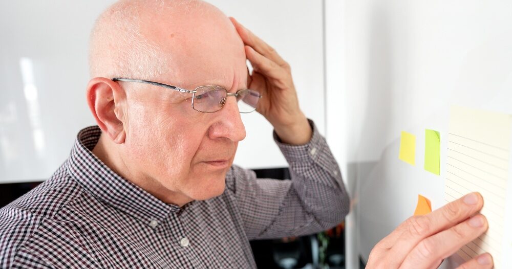 A senior looks at a board confused, representing one of the potential signs of dementia.