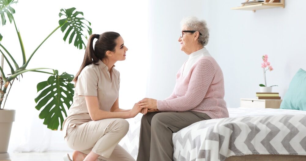 Communicating as a caregiver involves patiently and compassionately listening, as this caregiver is doing with her senior client.