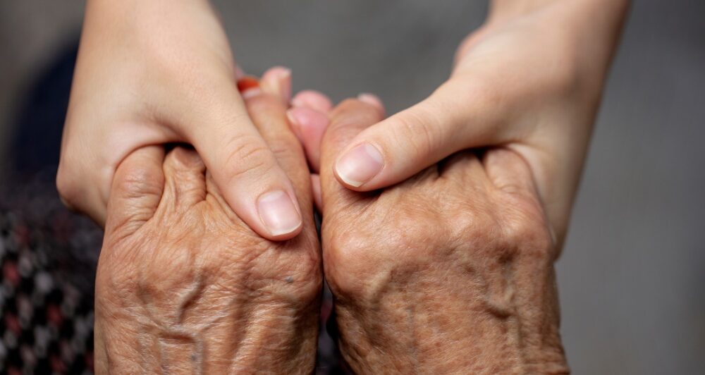 Younger hands hold older ones, representing the care and compassion of caregiving and how caregivers can help, even in ways like implementing stroke prevention strategies.