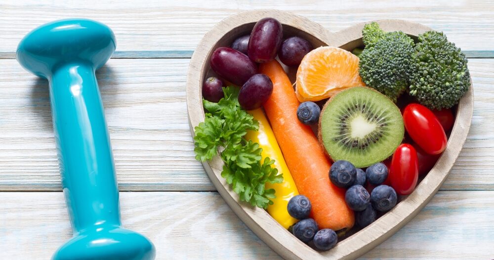 A heart with nutritious food and a dumbbell represents the healthy lifestyle that National Cholesterol Education Month promotes.