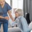 A caregiver demonstrates her caregiver skills by helping an older adult get up.