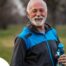 An older man smiles with a water bottle while exercising, representing the benefits of encouraging exercise when caring for seniors at home.