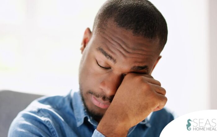A man tiredly rubs his eyes, representing the exhaustion that can come with family caregiving.