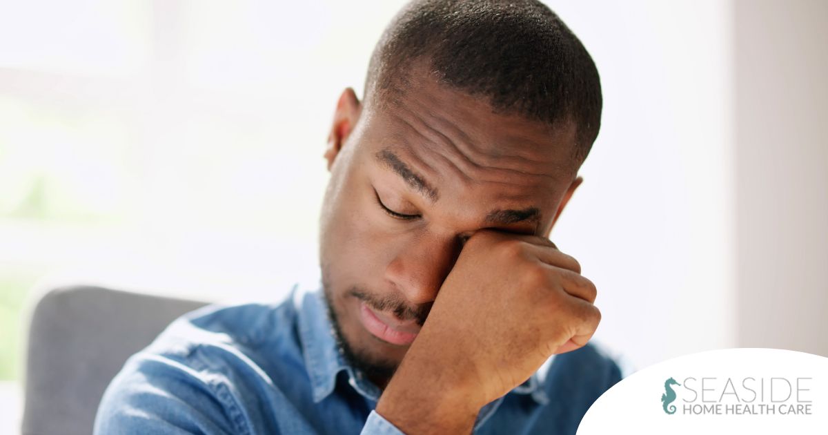 A man tiredly rubs his eyes, representing the exhaustion that can come with family caregiving.